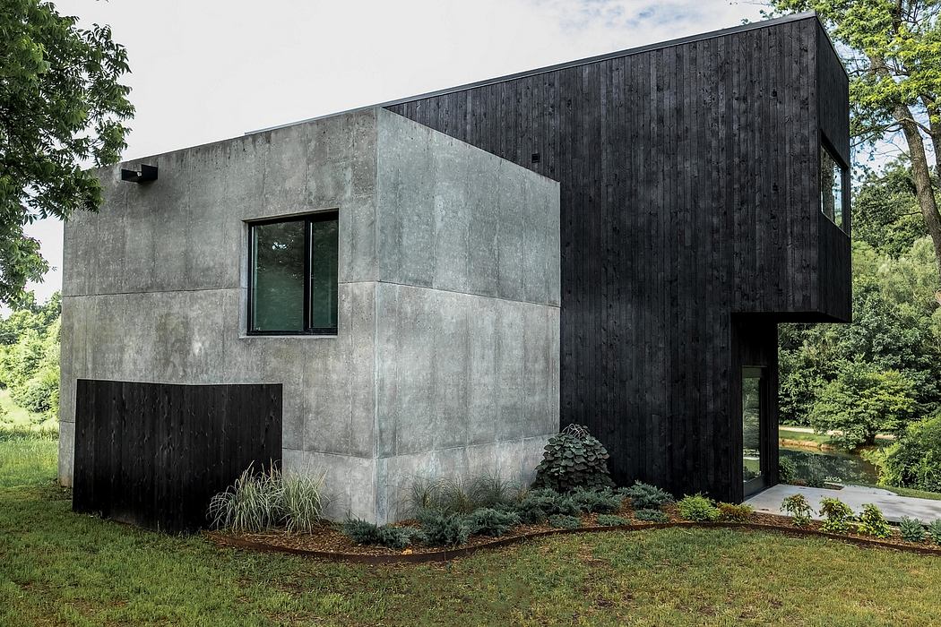 A modern concrete and wood structure with geometric forms and a serene natural setting.