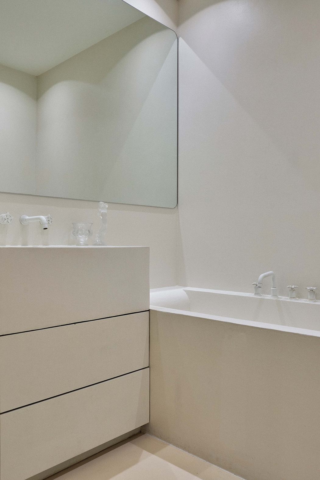Minimalist bathroom with built-in vanity drawers, wall-mounted mirror, and modern faucet.
