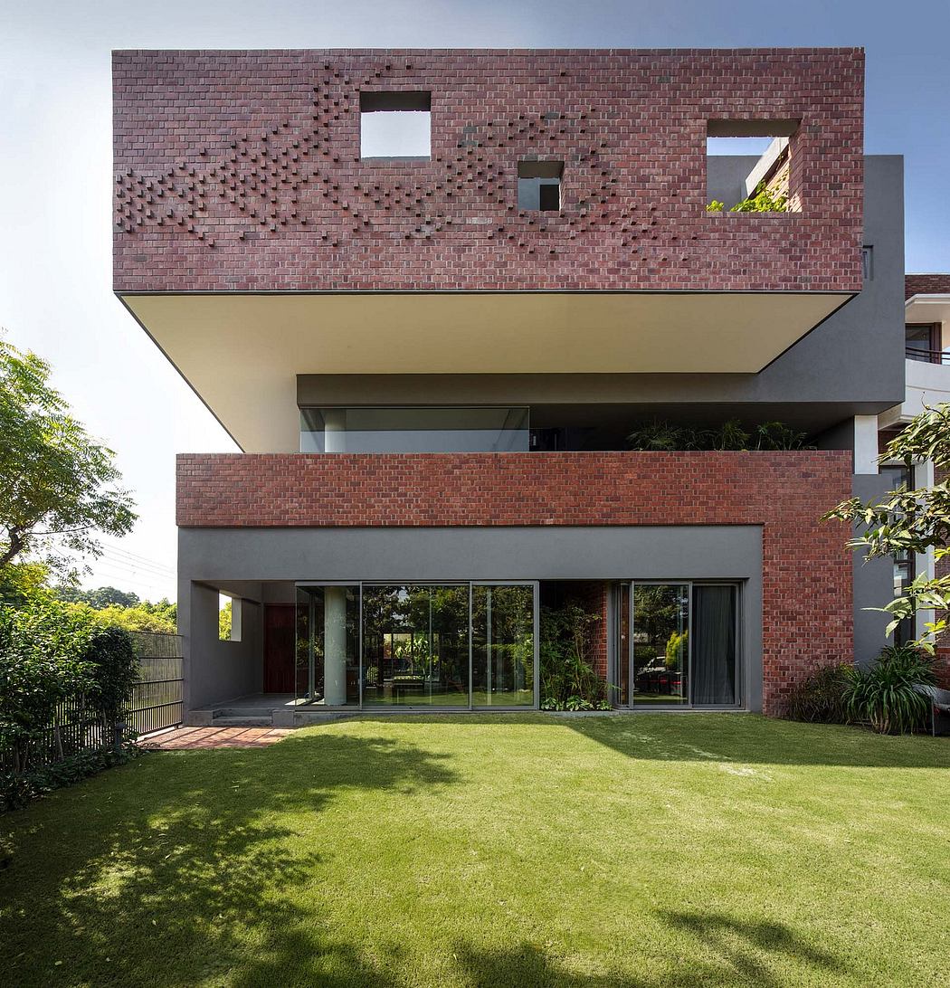Contemporary brick building with geometric window patterns, expansive glass walls, and lush landscaping.