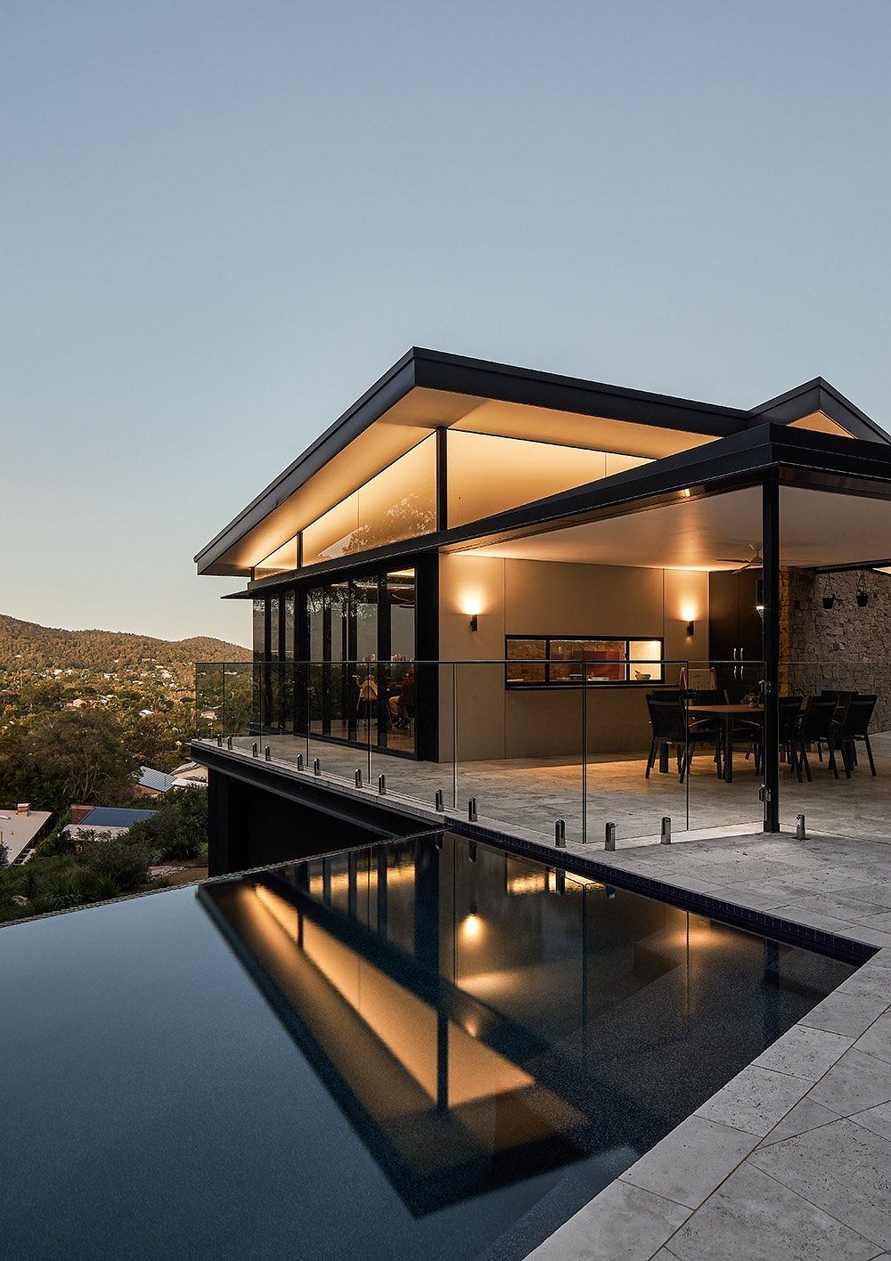 Sleek modern architecture with floor-to-ceiling glass, pool, and distant mountain views.