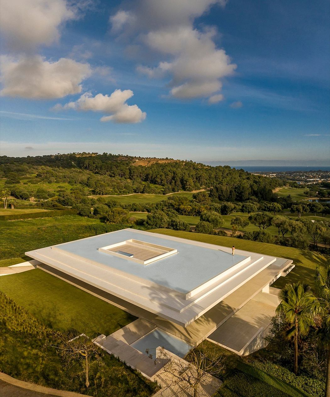 Striking modern architectural structure with geometric shapes and large windows overlooking scenic landscape.