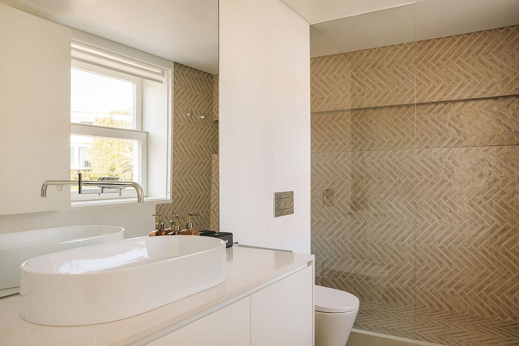 Sleek, modern bathroom design with herringbone tile wall and freestanding tub.