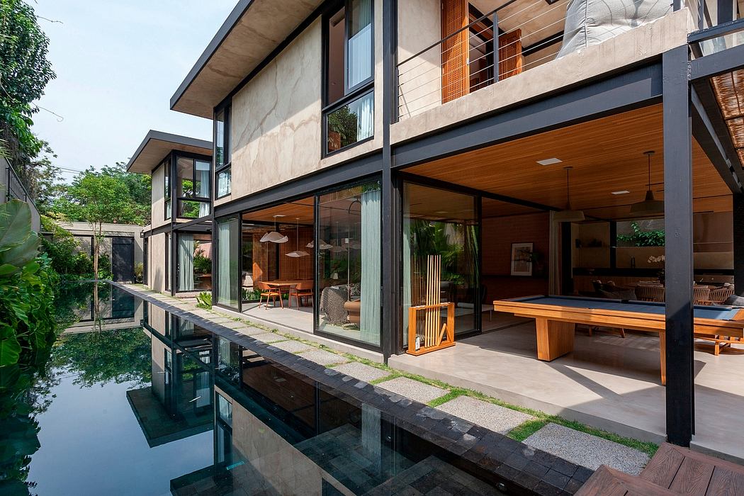 Modern tropical villa with glass walls, wooden deck, and reflection pool.
