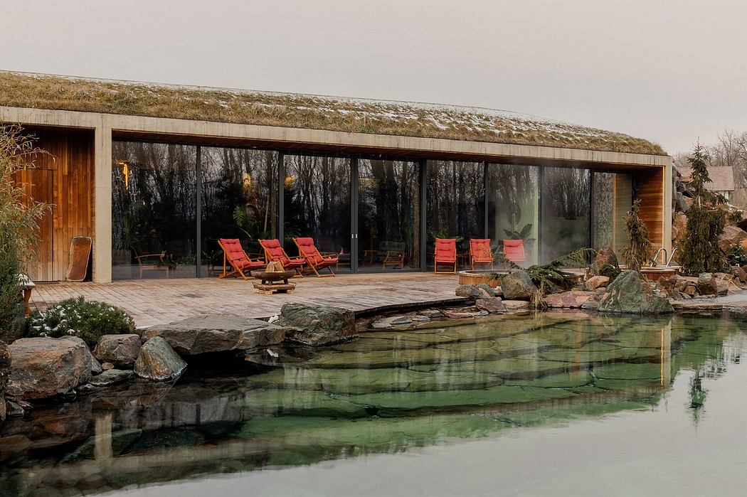 A modern wooden structure with a grass-covered roof overlooks a serene natural pool.