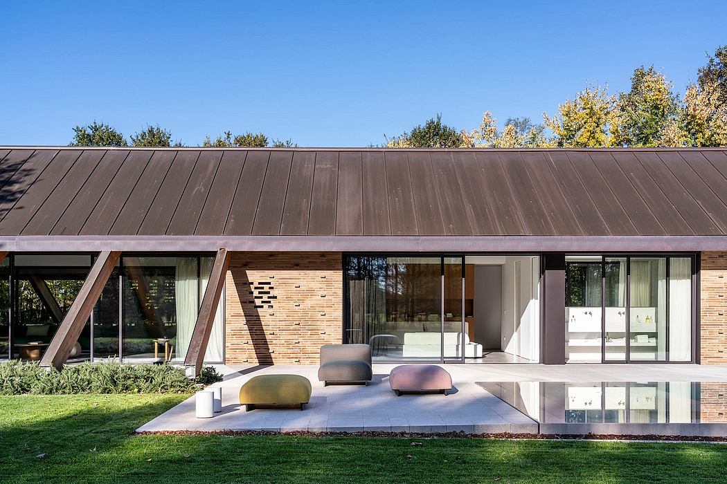 Modern single-story home with brick exterior, large glass windows, and minimalist patio furniture.
