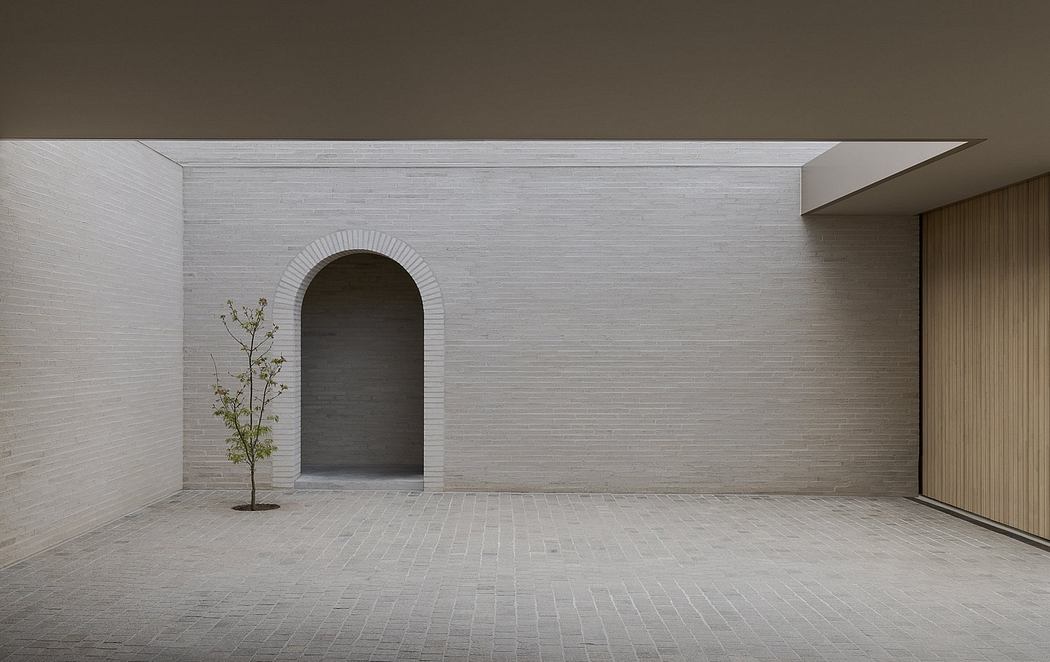 Minimalist architectural design with arched alcove, brick flooring, and a small tree.