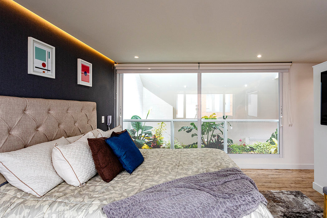 Large window with lush greenery outside, plush bedding, and vibrant artwork on dark walls.