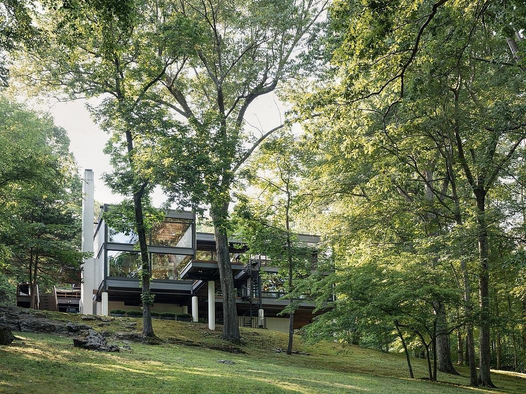 A modern glass and stone structure nestled in a lush forest, featuring distinct architectural elements.