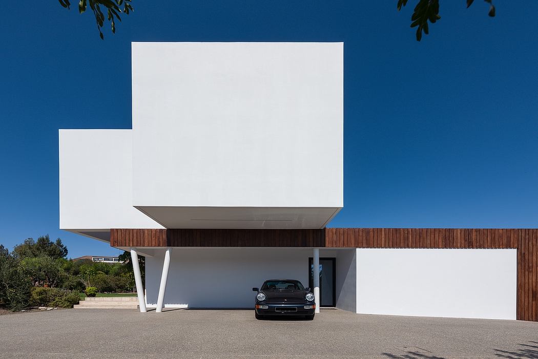 Modern white building with wooden elements and a parked car in the foreground.