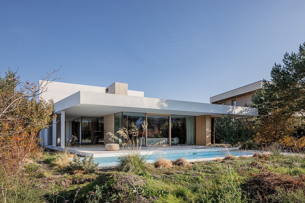 Minimalist modern home with floor-to-ceiling windows, pool, and lush landscaping.