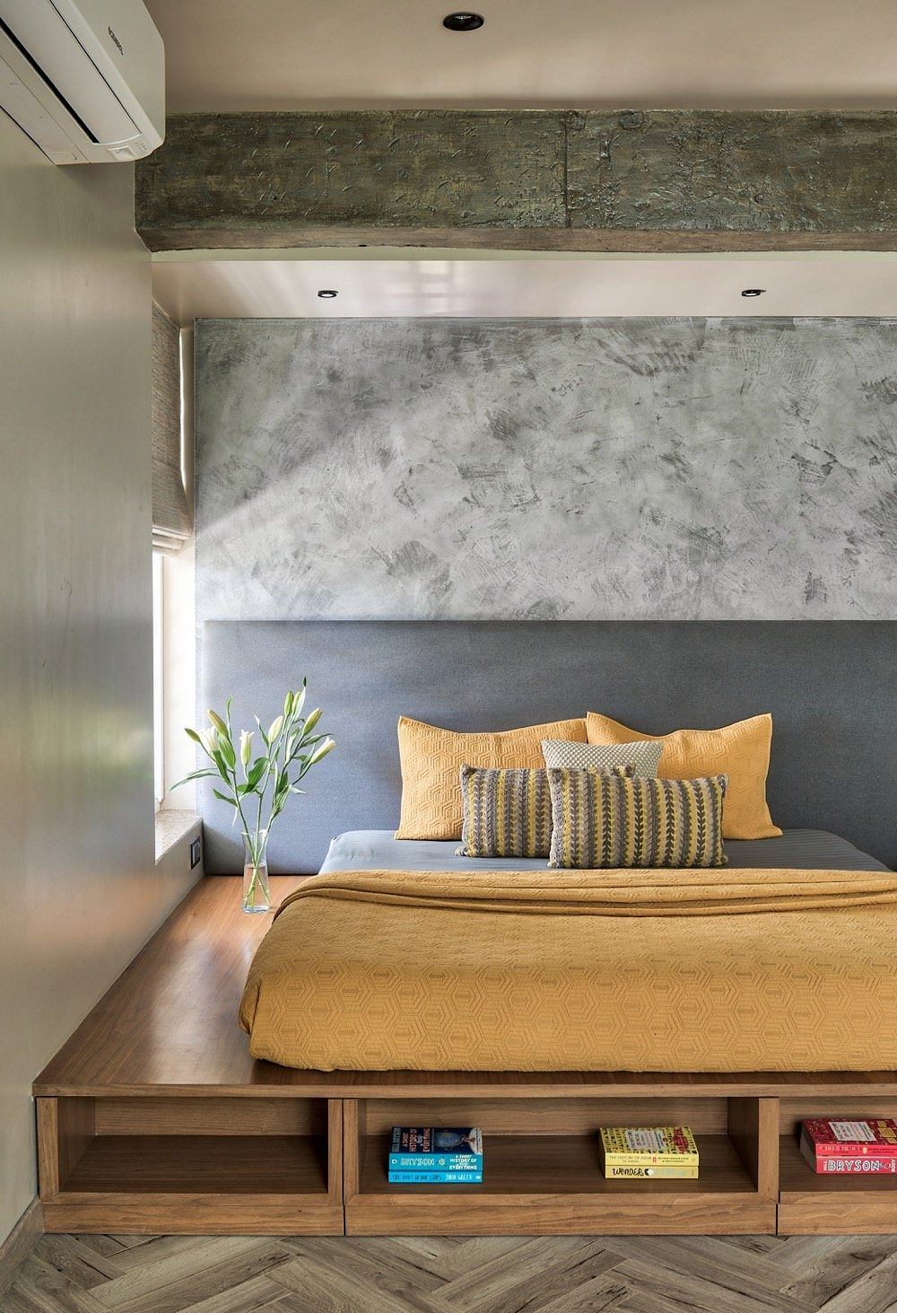 Rustic concrete ceiling beams, textured feature walls, and a wooden platform bed with storage.