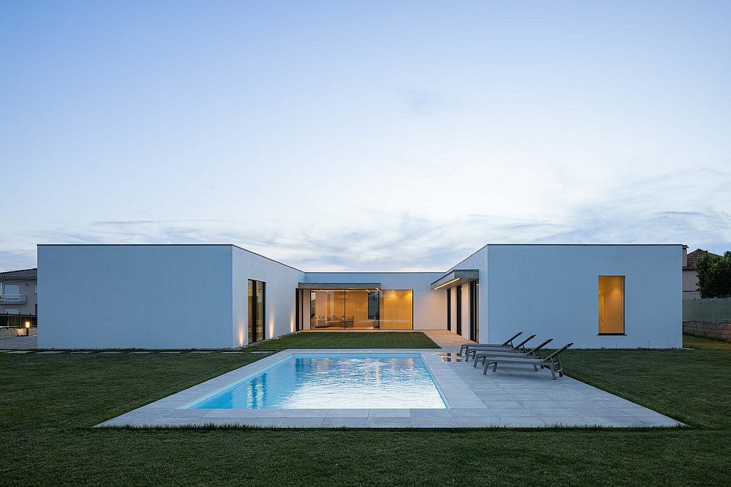 Striking modern architecture with pool, outdoor loungers, and illuminated interiors.