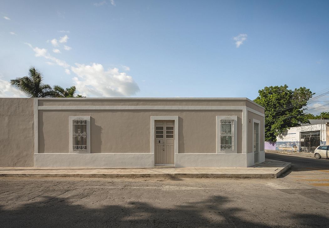 A single-story building with a gray exterior, barred windows, and a centrally located entrance door.