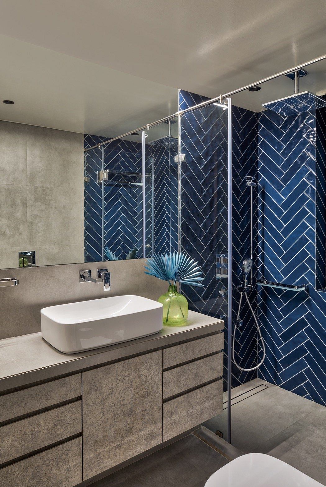 A modern bathroom with a striking navy blue chevron tile pattern and a sleek vanity.