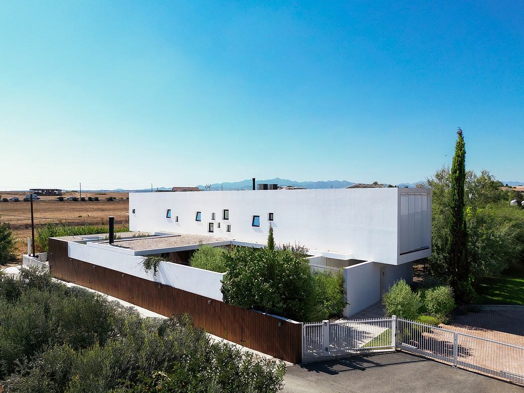 A modern, minimalist building with a white exterior, glass windows, and a wooden fence.