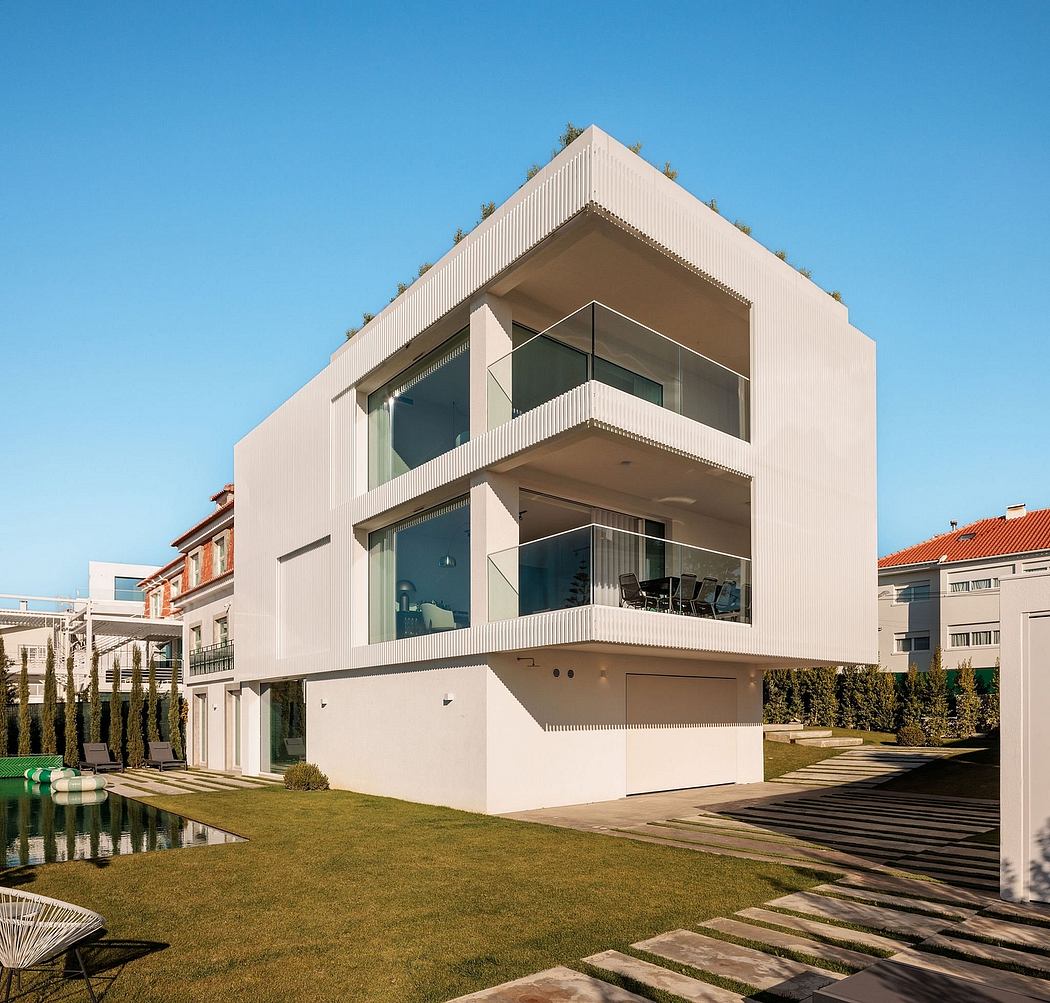 Sleek, modernist residential building with balconies, glass walls, and a manicured lawn.