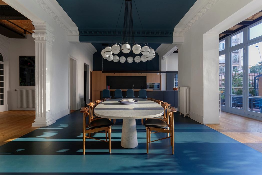 Stylish open-plan dining room with ornate chandelier, marble table, and vibrant teal floor.