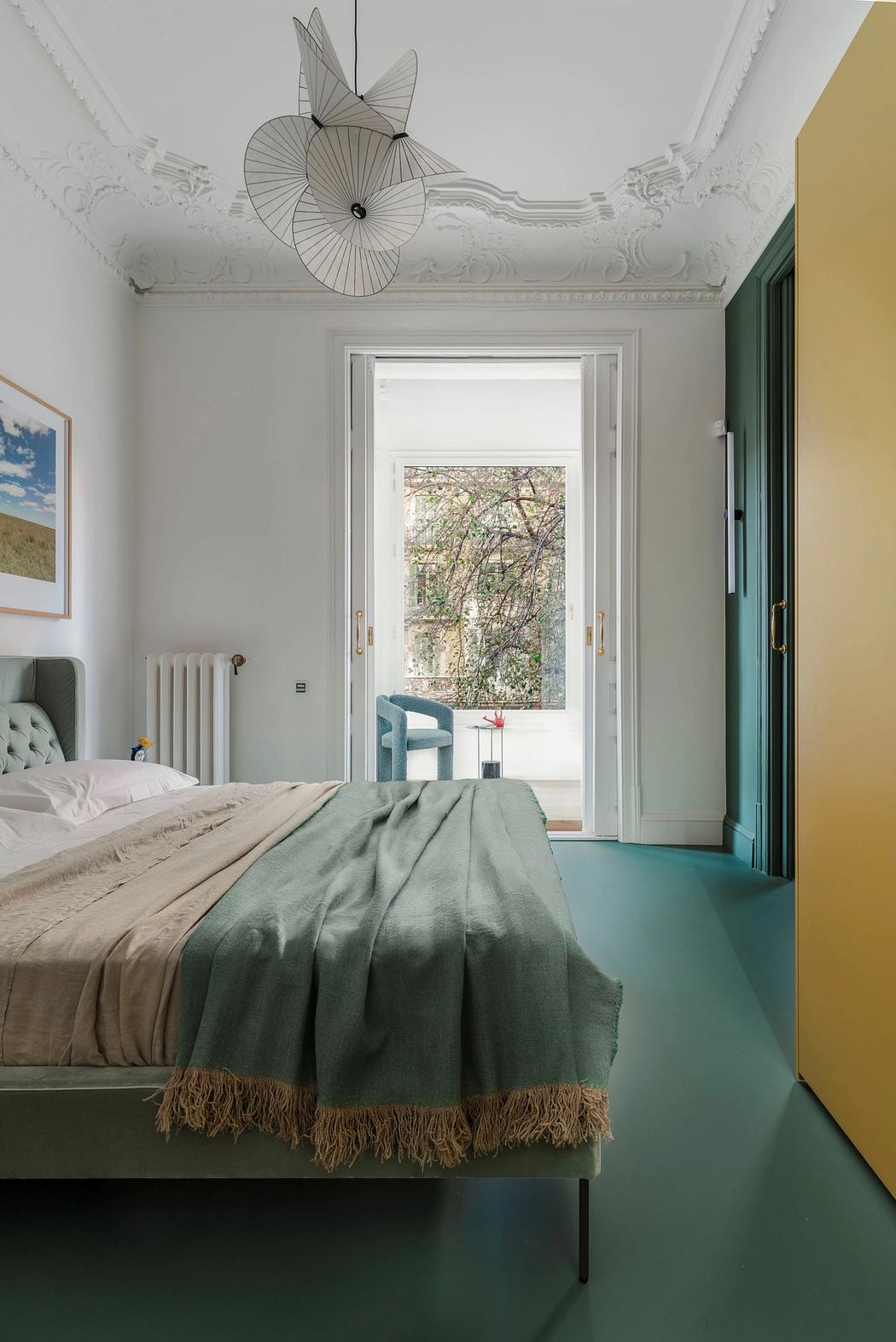 Ornate ceiling fixture, green accents, and scenic window view in this modern bedroom.