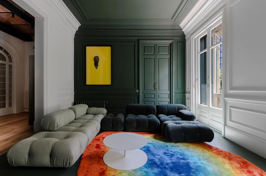 An ornate, modern interior with green paneled walls, plush sofas, and a rainbow-colored rug.