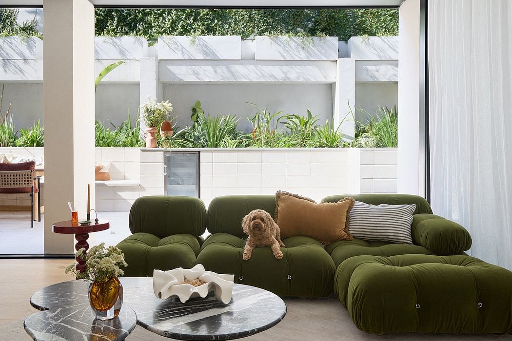 Lush, modern interior with verdant garden views through large windows, plush green sofas, and sleek, minimalist design.