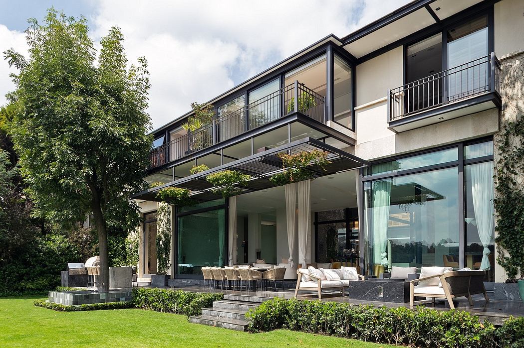 Sleek modern villa with expansive glass walls, balconies, and lush landscaping.