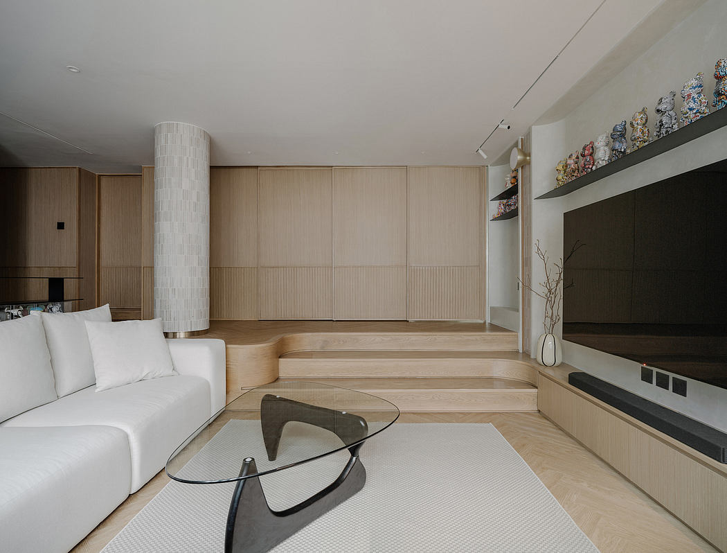 Minimalist living room with wooden panels, glass coffee table, and built-in storage.