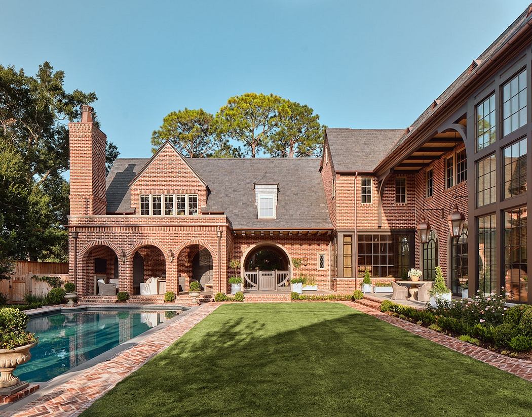 A majestic brick mansion with arched entryways, a serene pool, and lush landscaping.