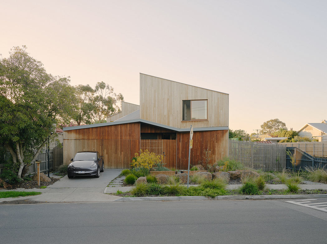 Modern wooden house with angled roof, solar panels, and landscaped yard.