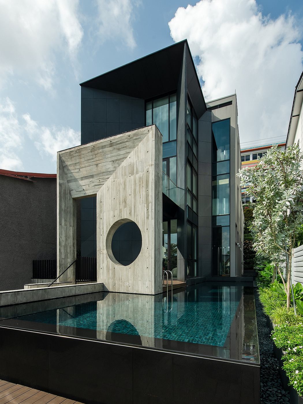 The building features a bold, angular design with a circular concrete element and a pool reflecting its facade.