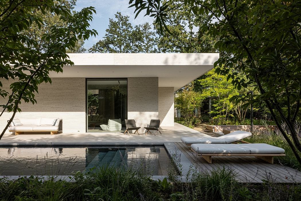 A modern, minimalist poolside pavilion nestled in lush greenery, featuring clean lines and sleek furnishings.