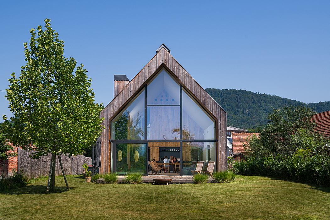 Sleek modern wooden structure with expansive glass facade and deck overlooking lush greenery.