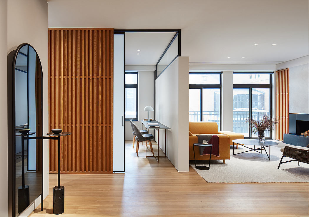 Minimalist living space with wood paneling, large windows, and a cozy seating area.