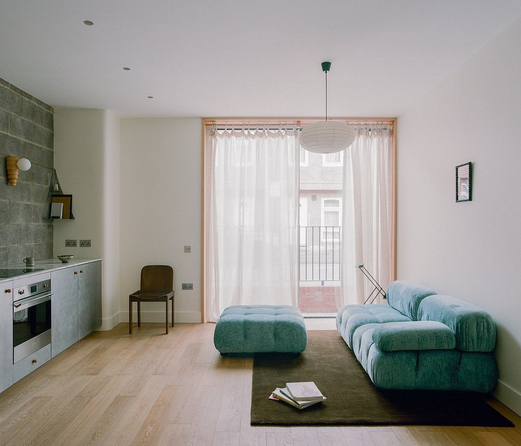Modern, minimalist living room with green upholstered furniture, large windows, and wooden flooring.