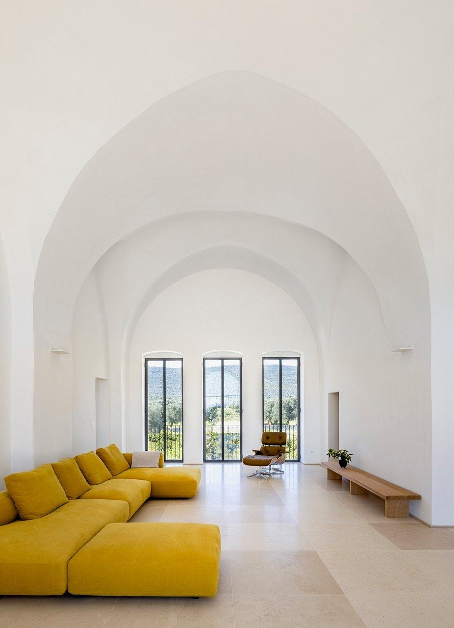 Spacious, light-filled room with vaulted arched ceilings, floor-to-ceiling windows, and a vibrant yellow sectional sofa.
