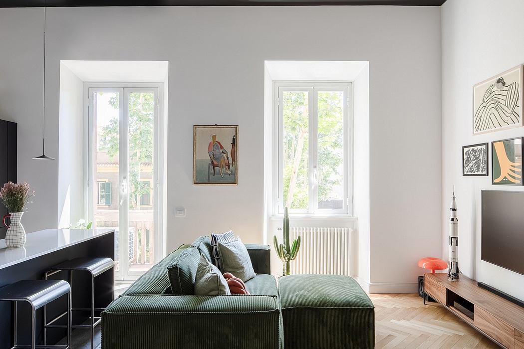 Spacious, modern living room with large windows, plush green sofa, and artistic decor.