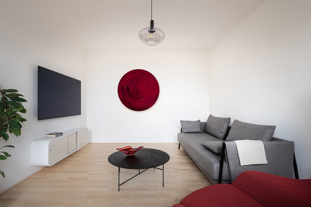 Minimalist living room with modern furniture, floating TV, and a bold red circular artwork.