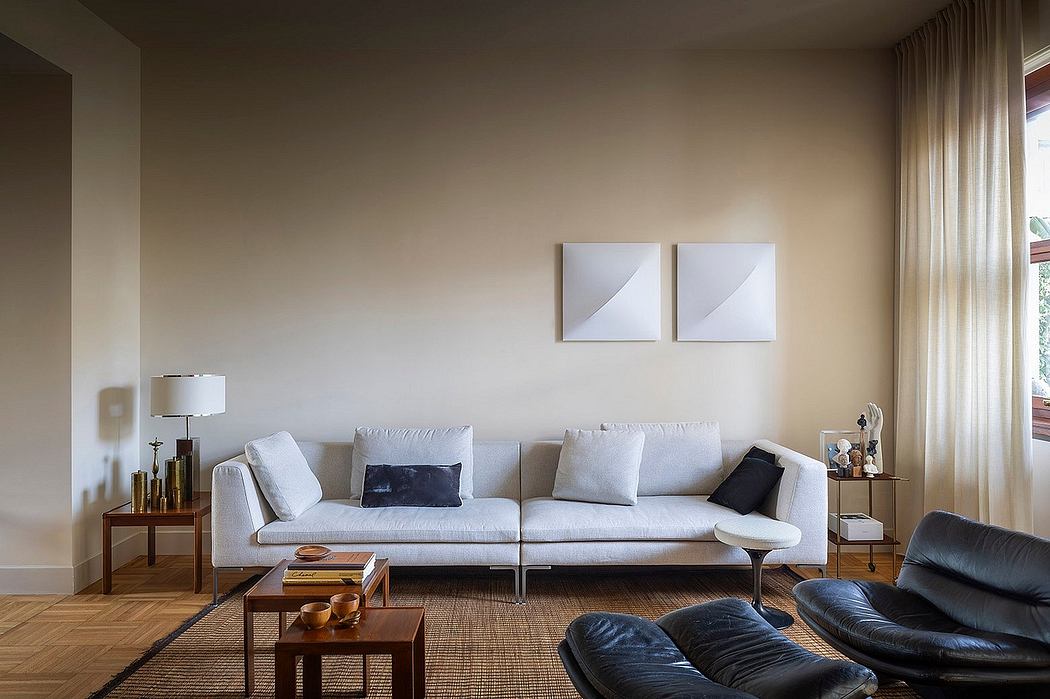 Minimalist living room with light gray sofa, dark leather chairs, and wooden accents.