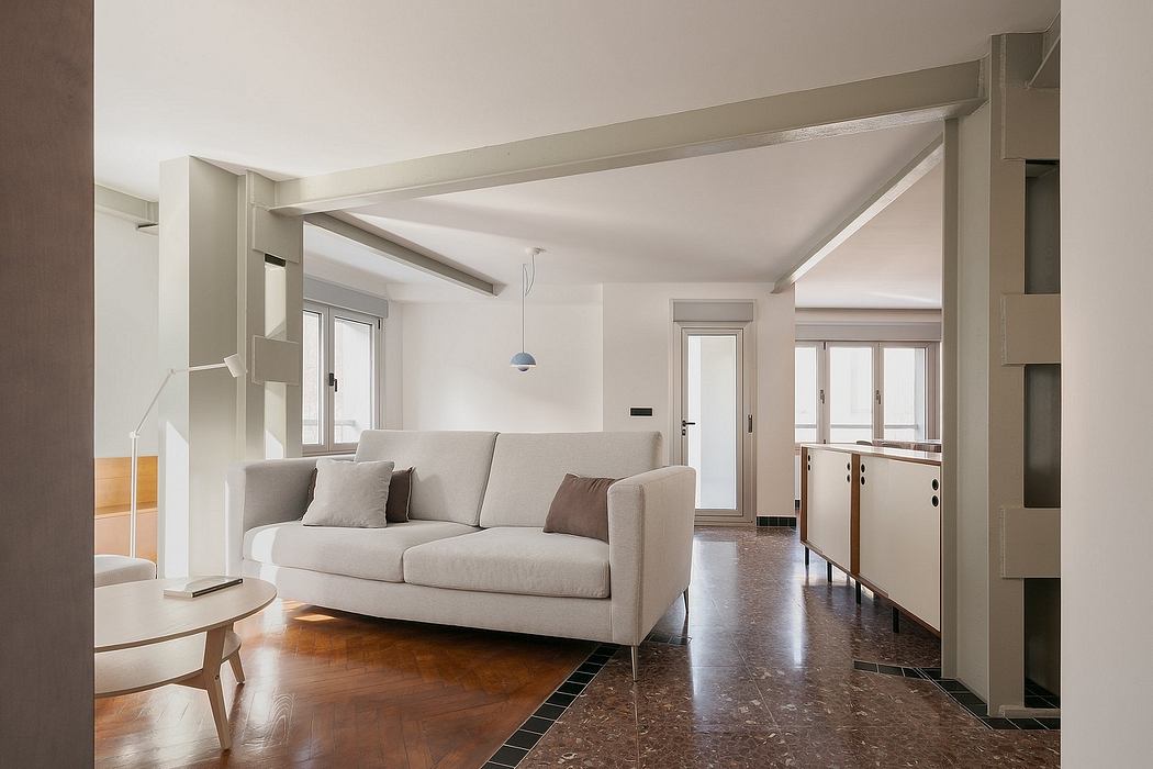 Minimalist living room with a sofa, pendant light, and wooden flooring with tile accents.