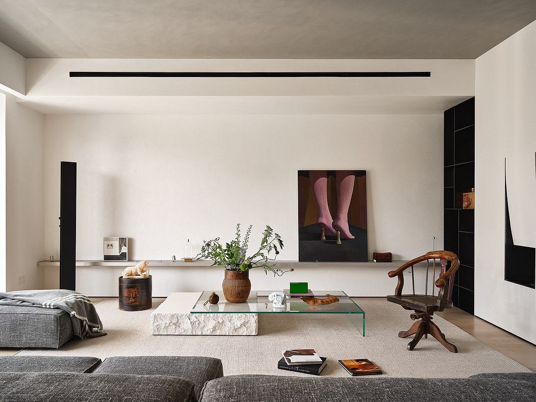 A minimalist living room featuring a glass-topped coffee table, potted plants, and an artsy wall decor.