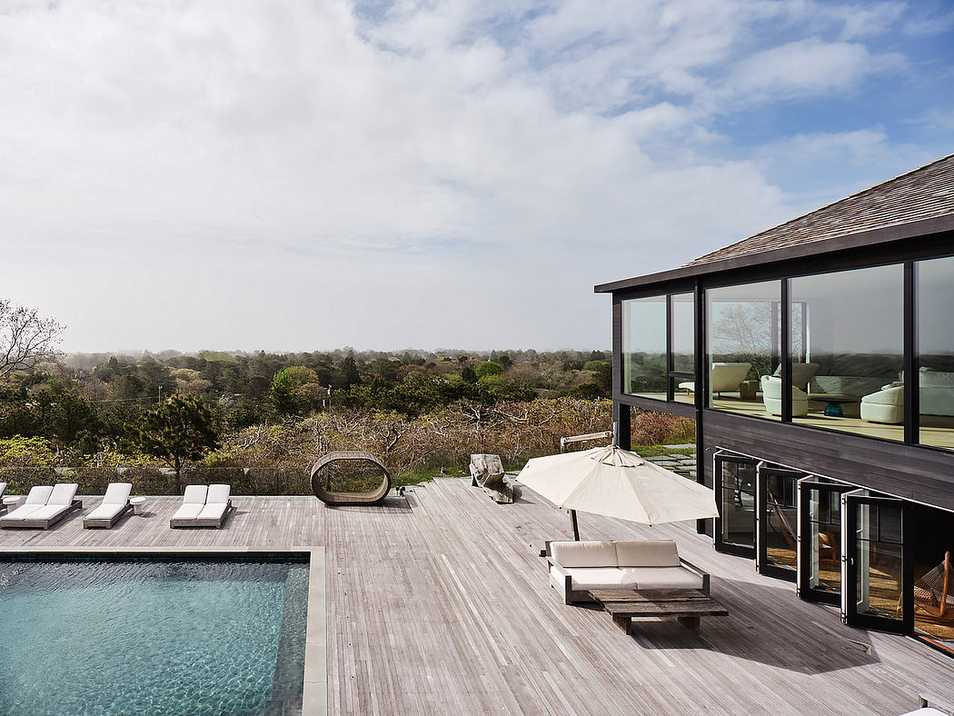 Minimalist outdoor deck with pool, lounge chairs, and panoramic forest views.
