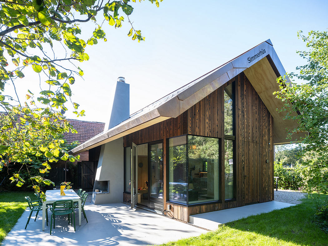Modern cabin-like structure with wooden exterior, large windows, and a deck surrounded by lush greenery.