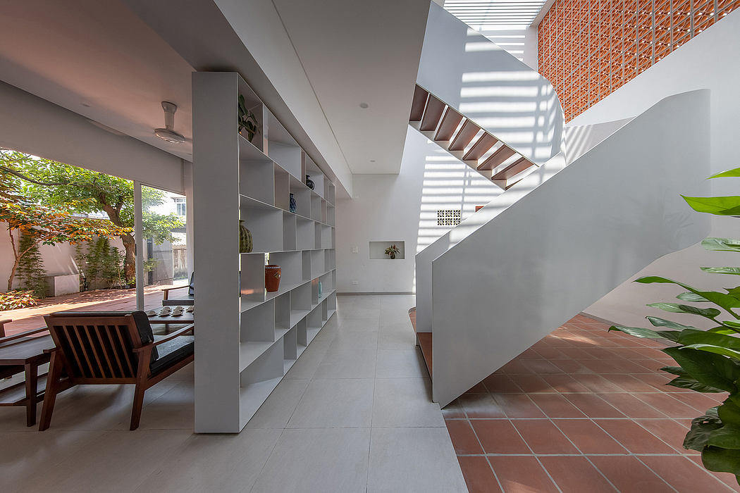 A modern, minimalist interior with a wooden staircase, open shelving, and natural elements.