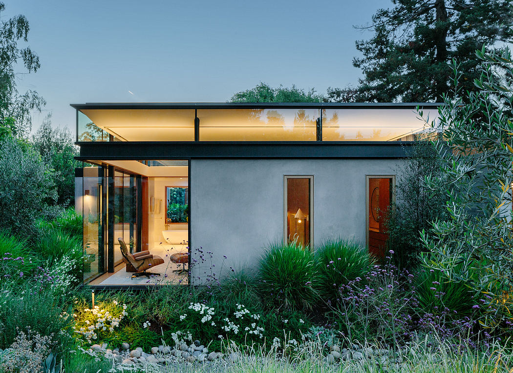 A modern home with a glass-enclosed porch surrounded by lush, colorful gardens.