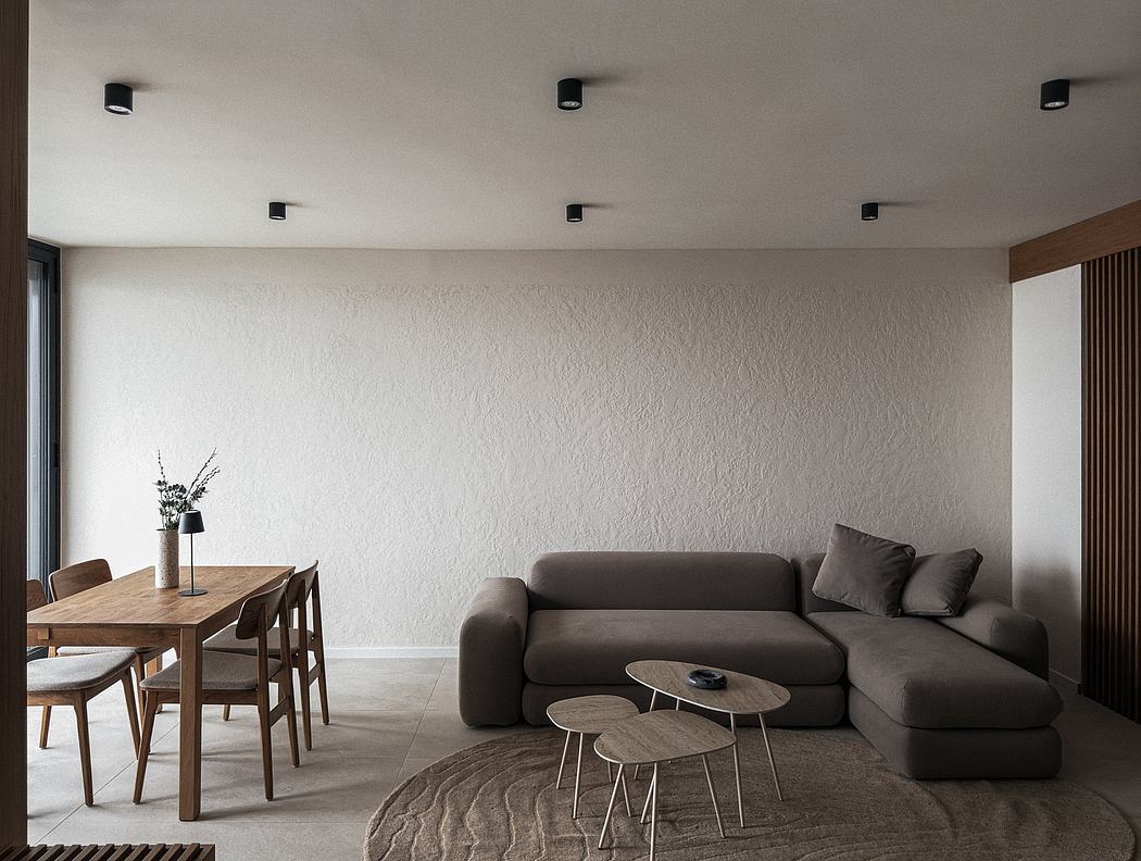 A minimalist living room with a wooden dining table, gray sofa, and round coffee tables.