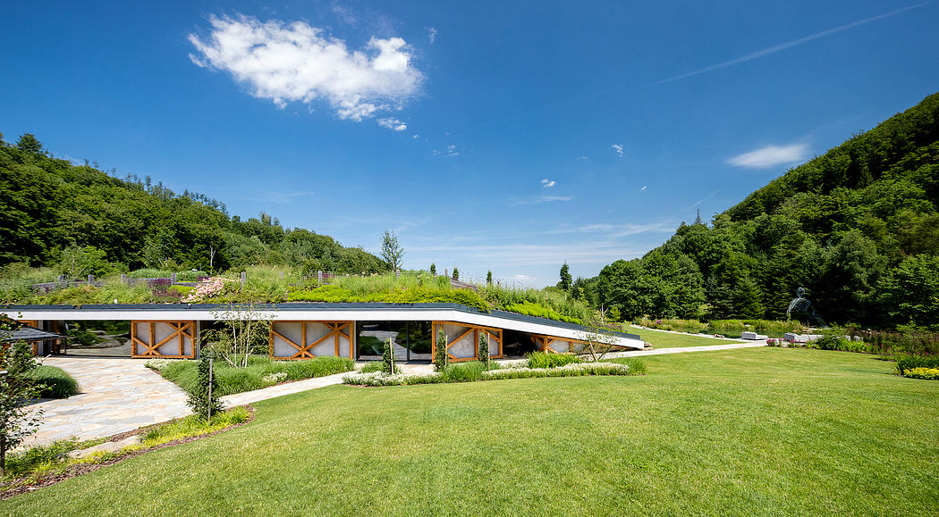 A modern glass and wood building surrounded by lush greenery and a well-manicured lawn.