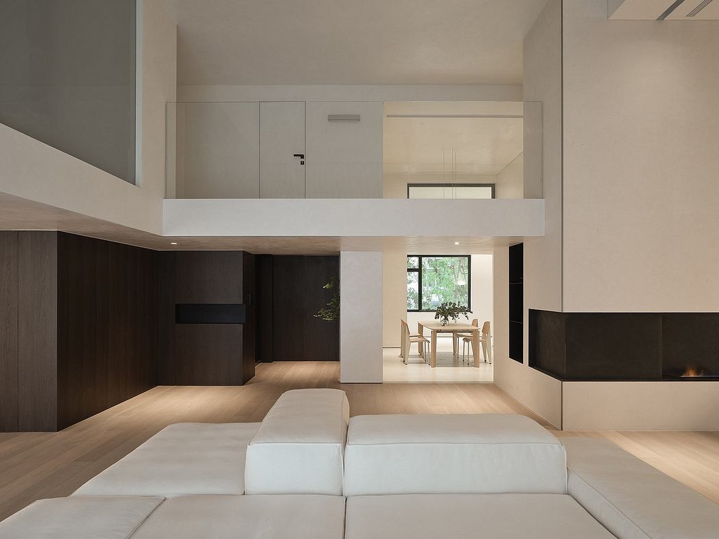 Minimalist open-plan living space with elevated sleeping loft, fireplace, and exposed wooden beams.