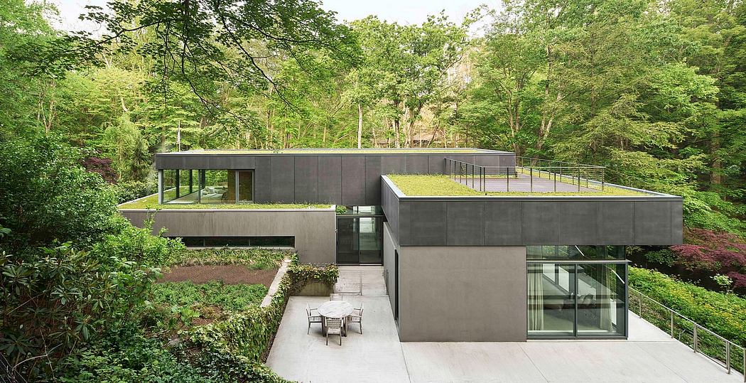 Modern, eco-friendly residential structure with green roof, surrounded by lush forest.