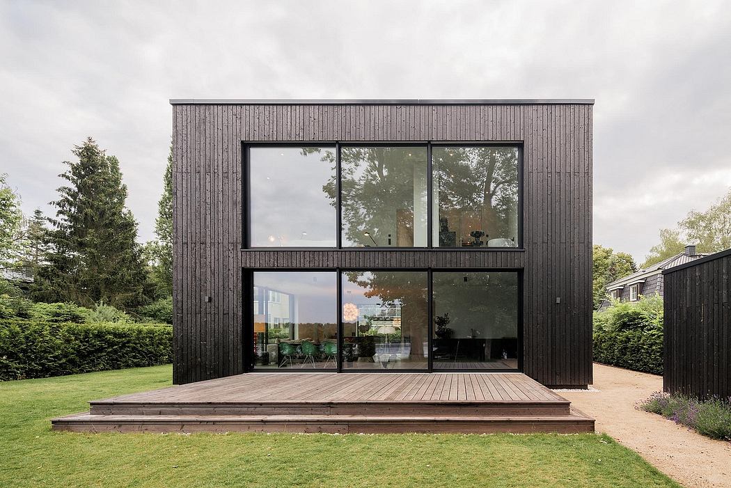 Sleek, modern exterior with large glass windows overlooking lush garden.