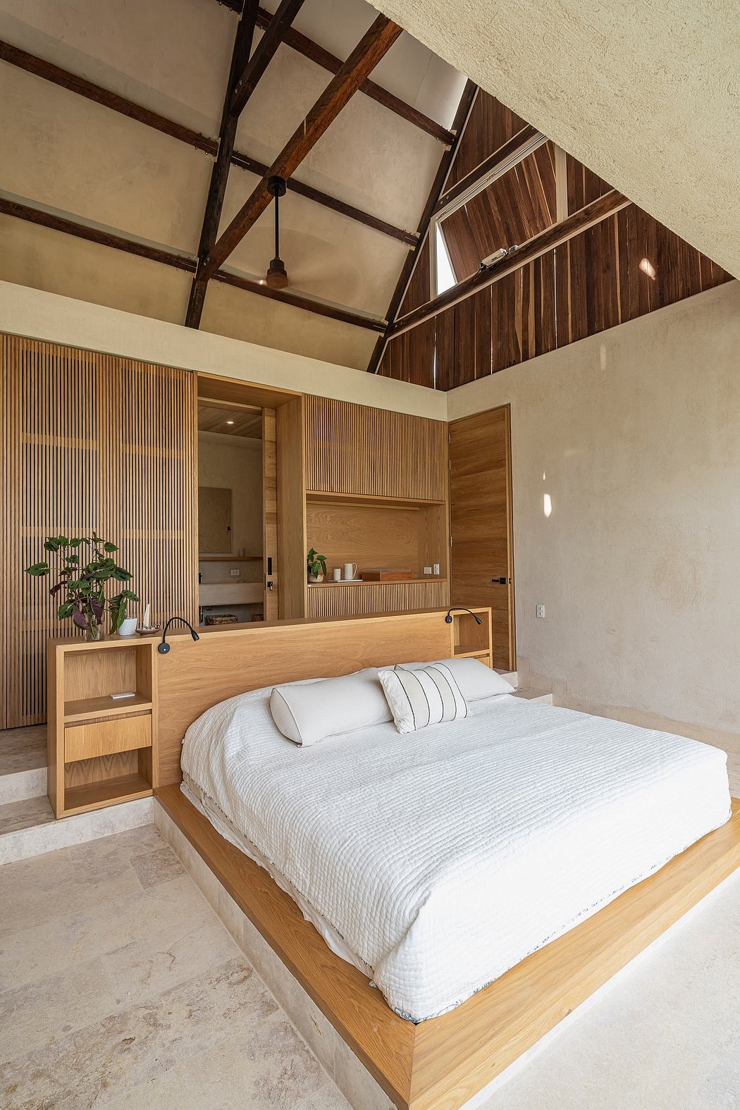 A spacious bedroom with a wooden-beamed ceiling, wooden paneling, and a minimalist design.