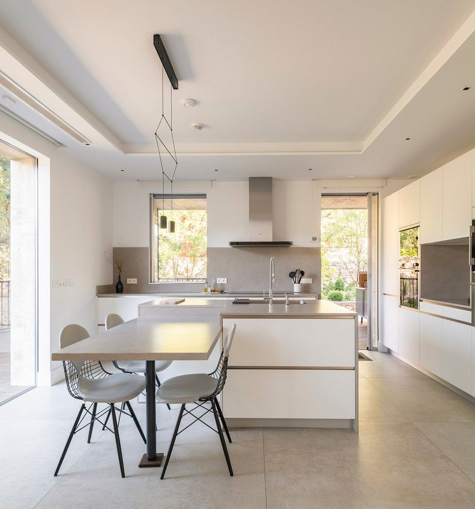 Modern, minimalist kitchen with clean lines, sleek cabinetry, and a centralized island. Abundant natural light and neutral tones create a serene atmosphere.